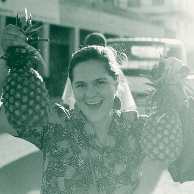 Kellie holding up two pineapples at a street market in Uganda