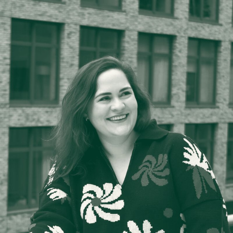Kellie Ojeda smiling, in a black sweater with white and red flowers